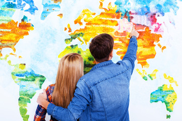 Whole world is opened for us. Two students cuddling and pointing on the map of the world