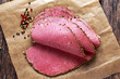 © grinchh - Peppered roast beef pastrami slices on paper with grains of coloured pepper.