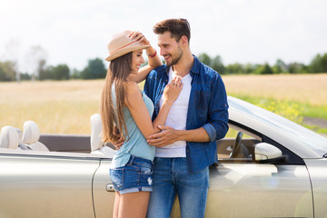 Wall Mural - Young couple standing near convertible
