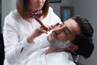 The barber woman shaves beard with razor and shaving foam
