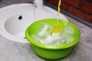 Fototapete - Sterilizing baby bottles in plastic green basin
