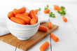 Small baby carrots in soup plates on cutting board