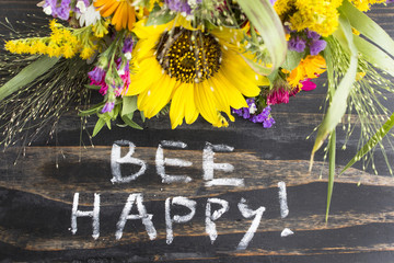 Words Bee Happy with Summer Flowers on a Rustic Wooden Backgroun