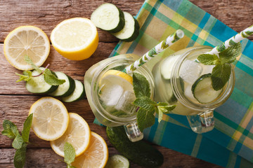 Wall Mural - Homemade cucumber lemonade with ice and mint macro in a glass jar. horizontal top view
