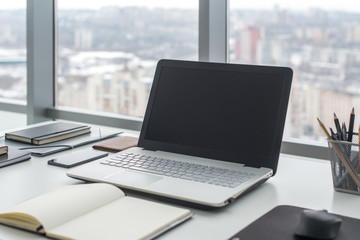 Workplace with notebook laptop Comfortable work table in office windows and city view.