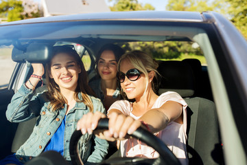 Wall Mural - happy teenage girls or young women driving in car