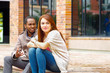 © Fotos 593 - Interracial happy charming couple sitting on steps in front of building interacting and smiling for camera