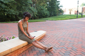 Wall Mural - An african american college student with a cell phone and headphones