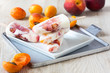 Peach apricot popsicles on white plate with fresh fruits