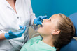 © sandyche - happy little girl with open mouth undergoing dental treatment at clinic. Dentist checked and curing teeth a child patient in the dental office