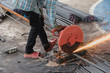 Construction builder worker with grinder machine cutting metal reinforcement rebar rods at building site and unsafe