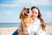 Tender Smiling Young Woman Hugging Her Dog On The Beach