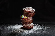 A Pile Of Cup Cakes On A Black Background