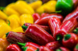 Fresh red, yellow, and green jalapeno chilis on a market stall. Selective focus.
