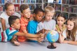© WavebreakmediaMicro - School kids looking at globe in library
