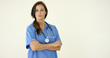 © Dash - Woman in scrubs crosses arms and smiles at camera with stethoscope around her neck