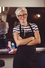 Female hairdresser standing with arm crossed at a salon