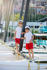 Canvas Print - Two beautiful children, boy brothers, standing on a boat, smilin