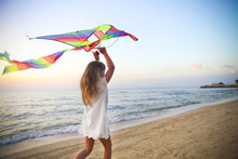 Little Girl With Flying Kite On Tropical Beach At Sunset
