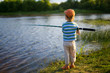 first fishing. child standing with a fishing rod on the shore