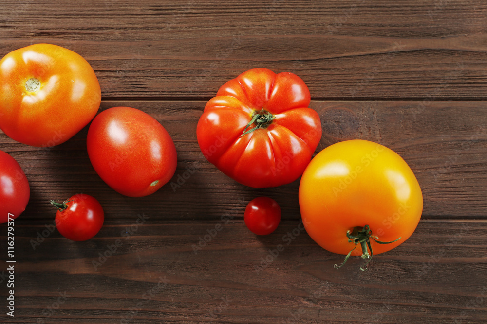 Different juicy tomatoes on wooden background