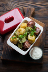 Wall Mural - Bowl with boiled three color pelmeni and sour cream, studio shot