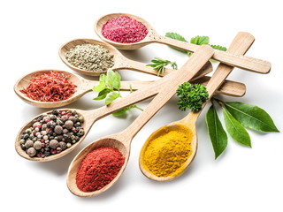 Assortment of colorful spices in the wooden spoons on the white