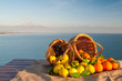 Wicker baskets full of oranges and lemons on a piece of jute with blue sea and Mount Etna in the background