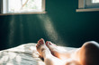 © RooM The Agency - Sunlight streaming through window onto woman's legs on bed