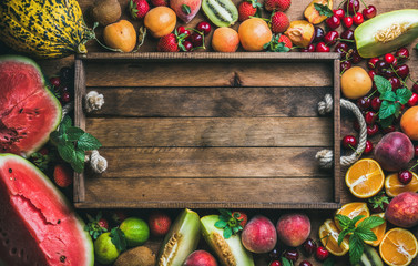 Summer fresh fruit variety with rustic wooden tray in center