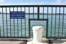 Concrete Jetty With Metal Railing And Sign Warning Children Must Be Supervised By Adults At All Times.