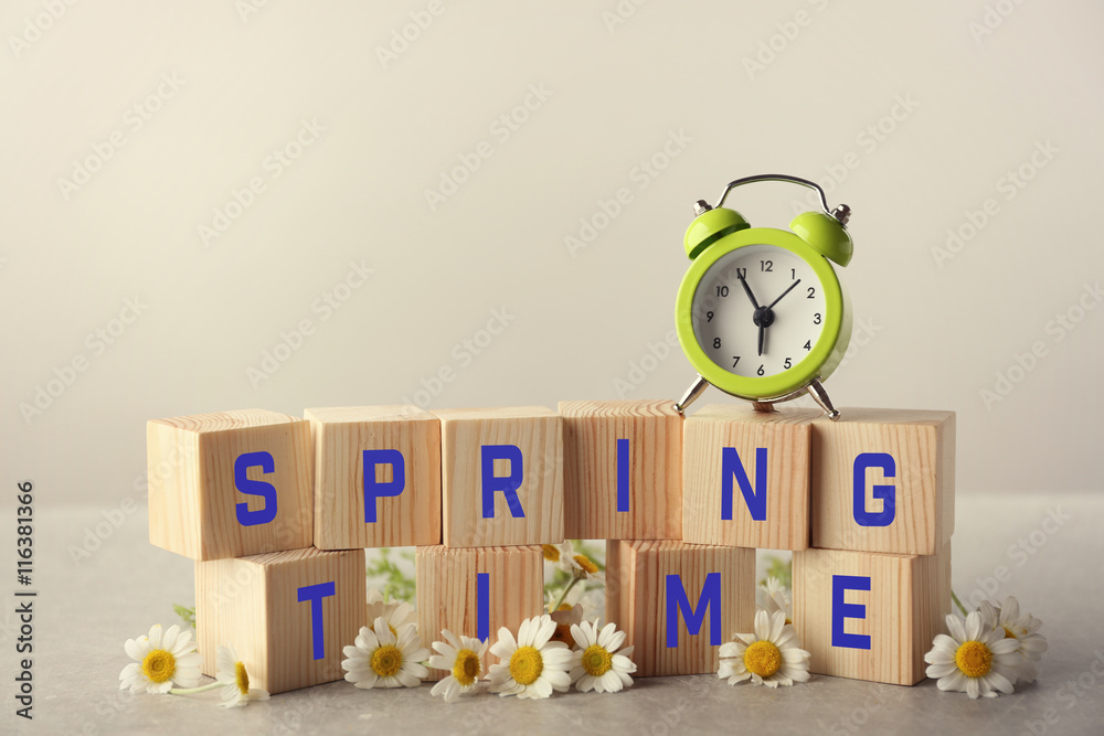 Clock, wooden cubes with space for text and chamomile on grey background