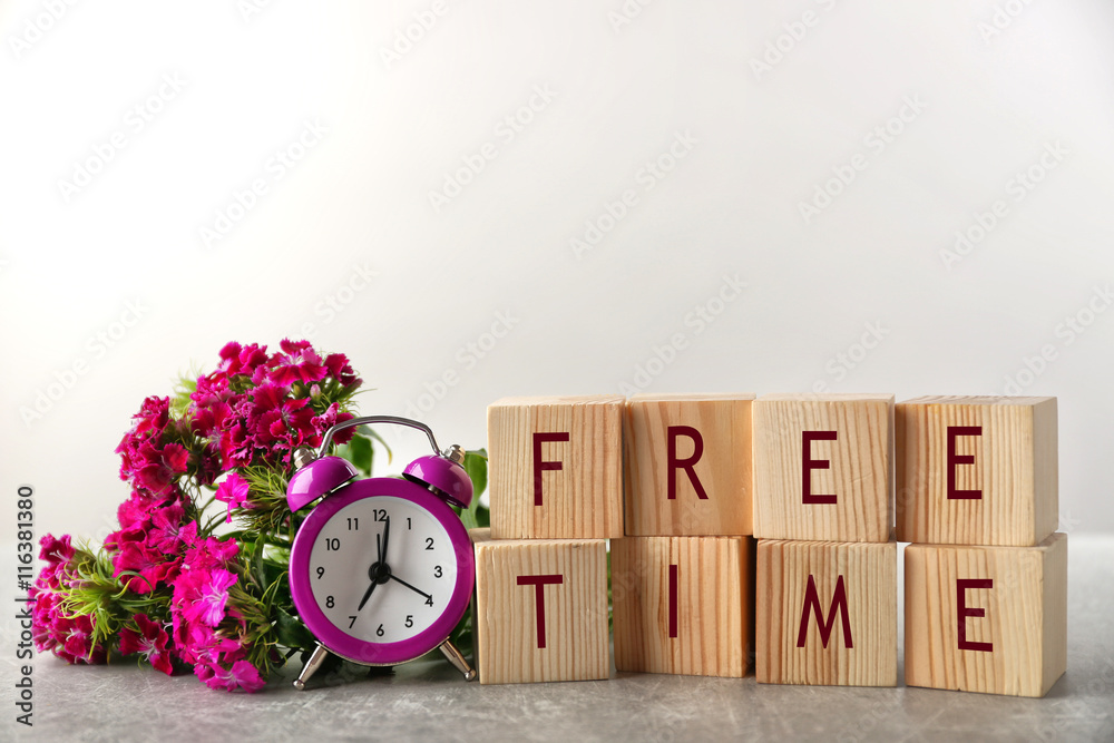 Wooden cubes with space for text, clock and flowers on grey background