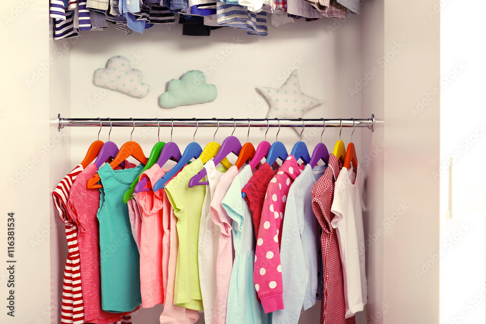 Children clothes hanging on hangers in the wardrobe