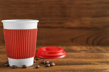 Poster - Paper cup of coffee on wooden background