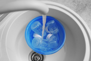 Fototapete - Sterilizing baby bottles in plastic blue basin