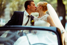 Fiance Kisses Pretty Blonde Bride Sitting On A Black Cabriolet