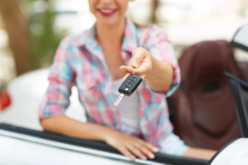 Woman standing near convertible with keys in hand - concept of b