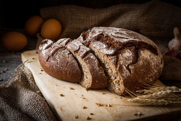 Sourdough rye bread sliced on wooden cutting board. Rustic still life. Natural light, low key