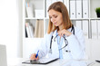 © rogerphoto - Female doctor  writing a medical prescription at clipboard