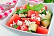 Watermelon, cucumber and feta cheese salad close up in square bowl on marble background