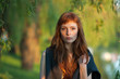 Young redhead caucasian woman serious face outdoor portrait in film retro colors