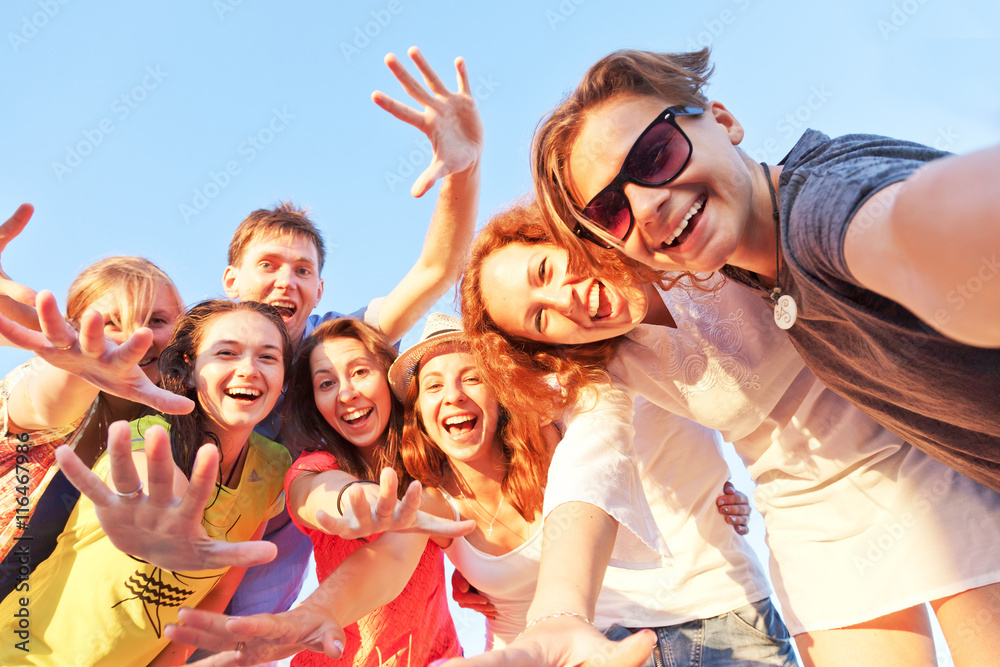 Group of happy young friends doing selfie against the blue sky. - obrazy, fototapety, plakaty 
