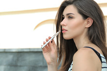 Beautiful Woman Smokes An Electronic Cigarette Outdoors
