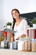 © lenets_tan - Young woman using a tablet computer to cook in her kitchen .
