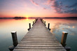 langer Holzsteg am Seeufer zum Sonnenaufgang im Sommer