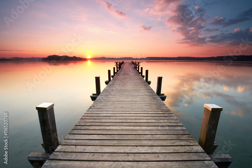 Obraz w ramie langer Holzsteg am Seeufer zum Sonnenaufgang im Sommer