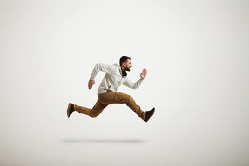 Young Caucasian man running violently over white background