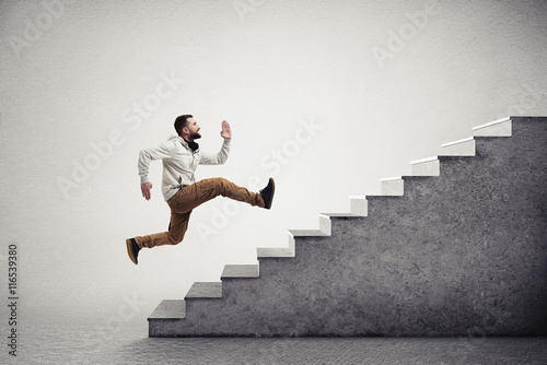 Fotografía Side view of young bearded man running violently up the grey sta