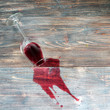 Dropped wine glass and spilled red wine on a wooden table as a symbol of fail, slight unpleasantness